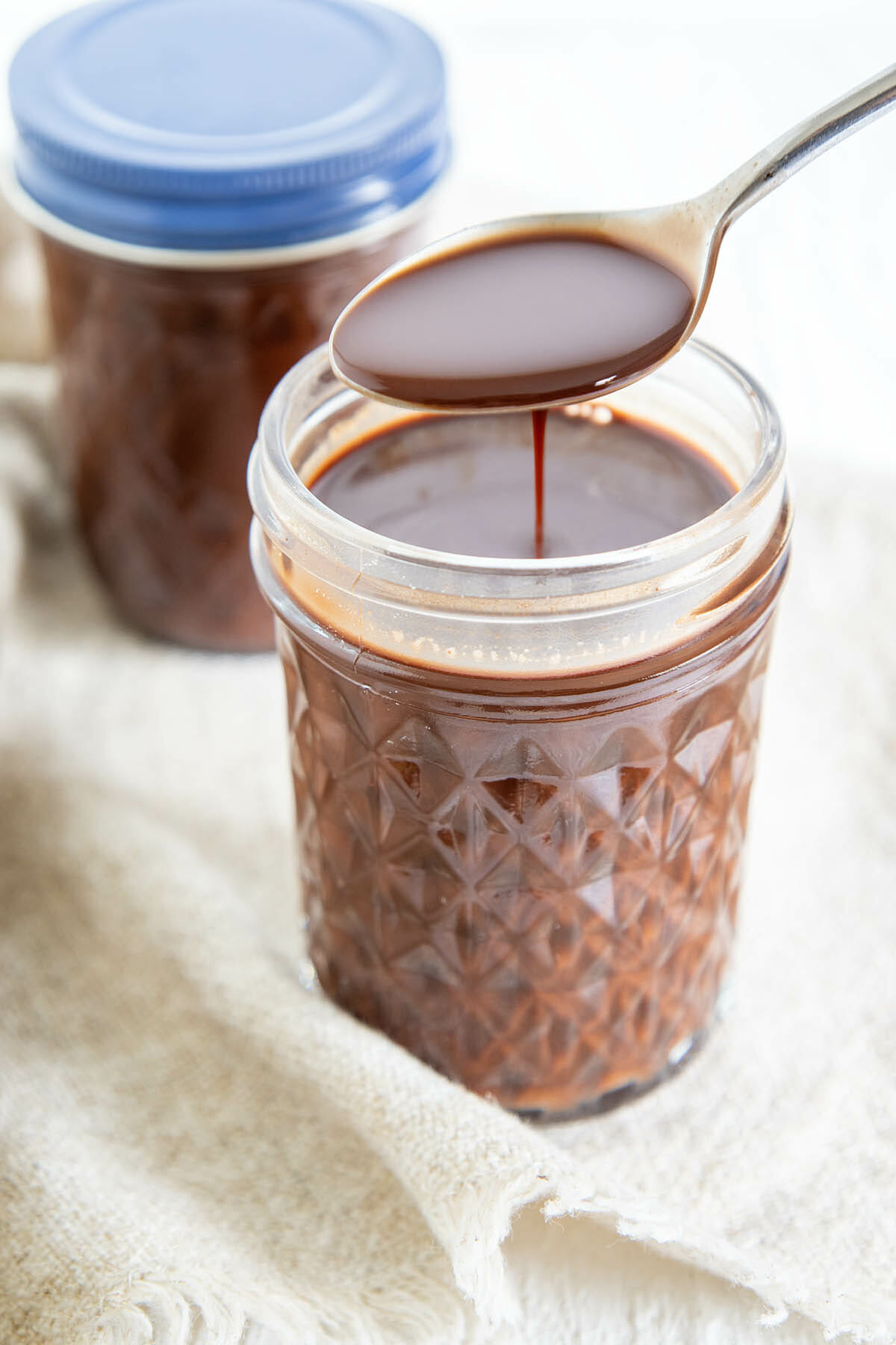 Spoonful of Chocolate Simple Syrup drizzling into mason jar.