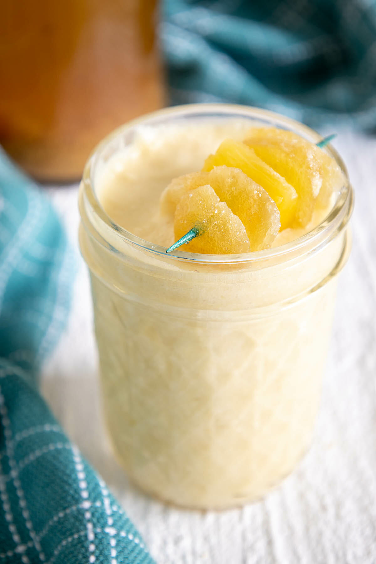 Ginger Pineapple Kombucha Mocktail in a glass with a candied ginger and pineapple garnish.