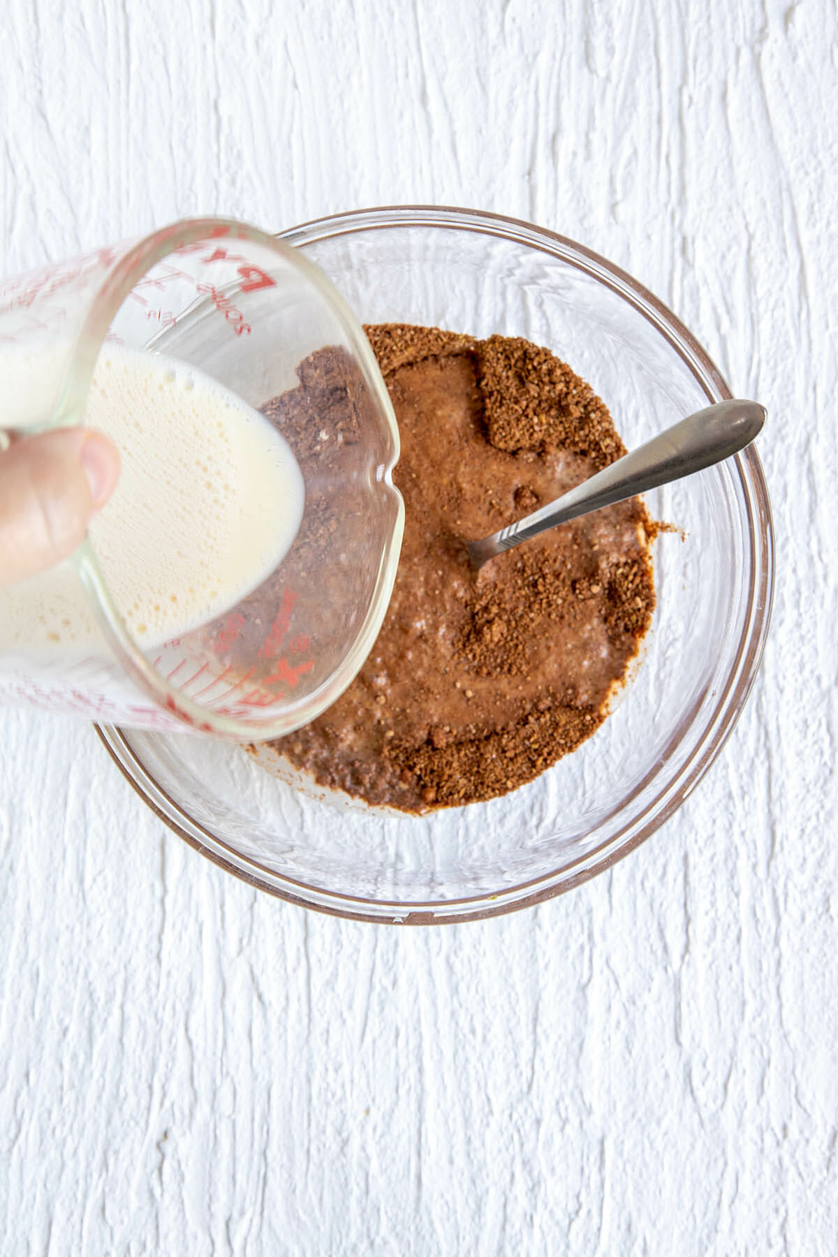 Wet ingredients being added to the bowl of dry ingredients.