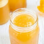 Passion Fruit Kombucha in a glass with bottles in the background.