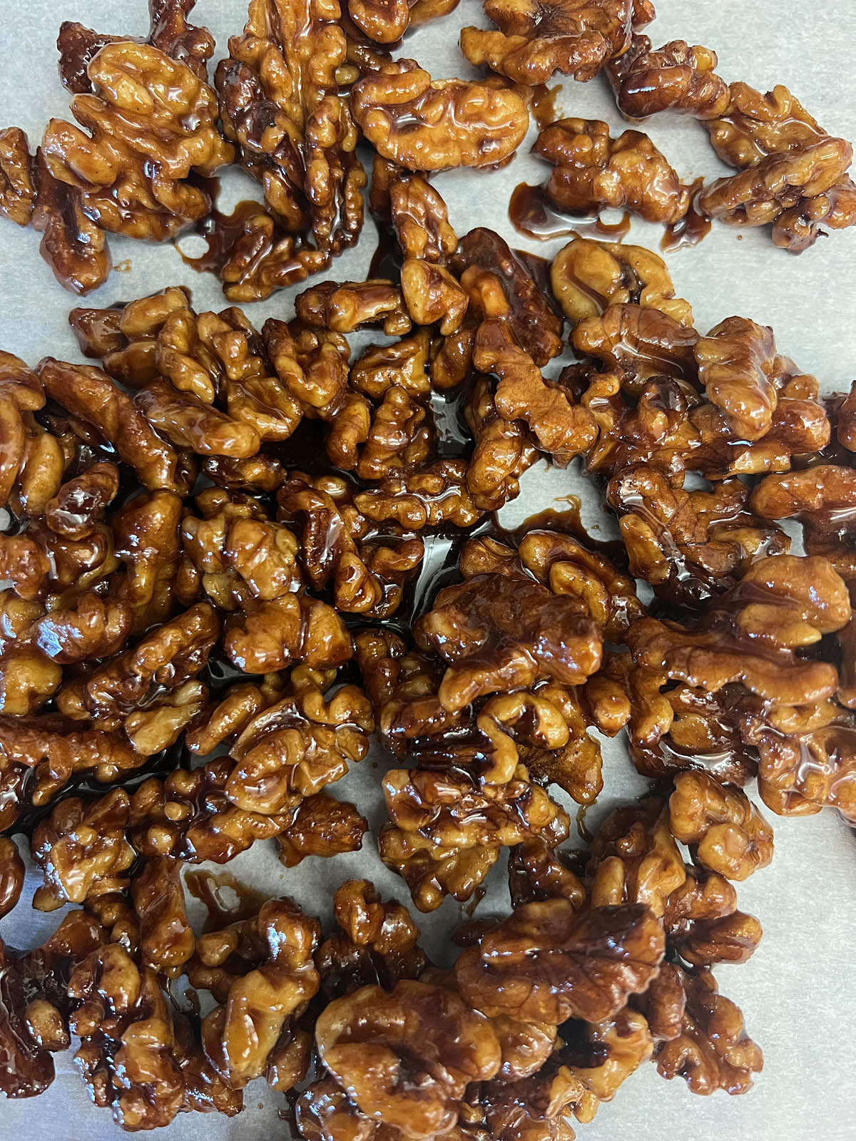 Candied walnuts spread on parchment paper.