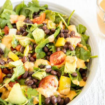 Vegan Southwest Salad in a bowl with pitcher of chipotle dressing.