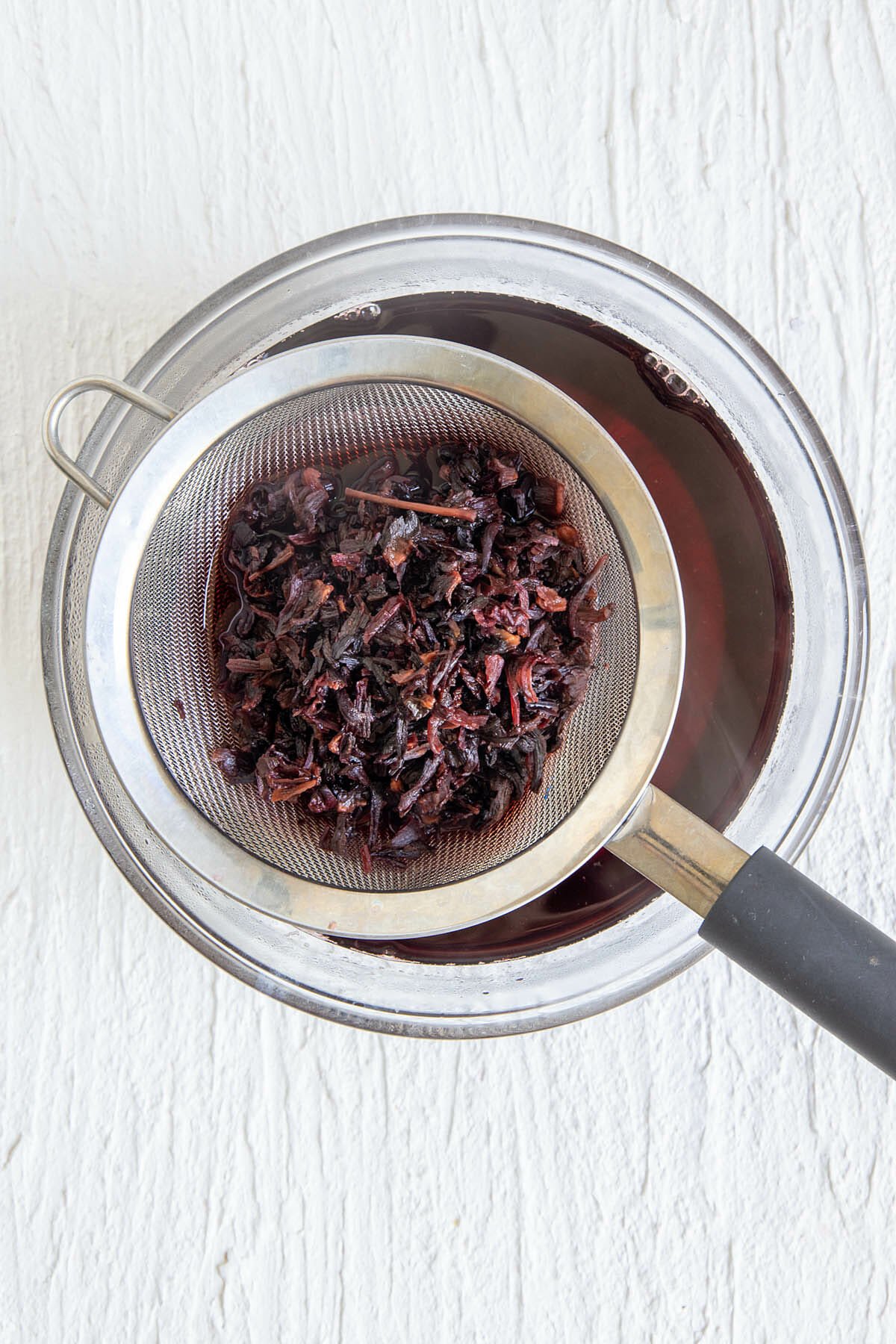Hibiscus flowers being strained out of tea.
