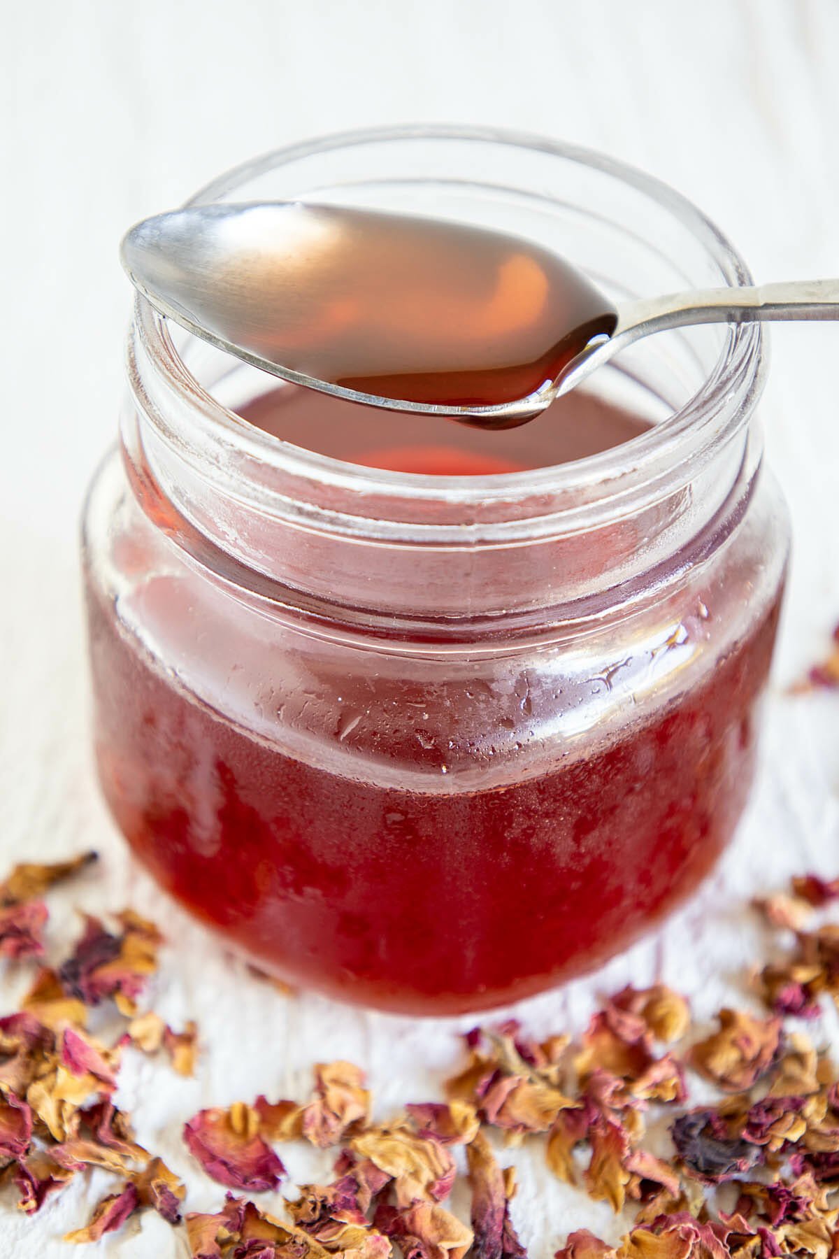 Rose Simple Syrup in a mason jar with spoonful on top.