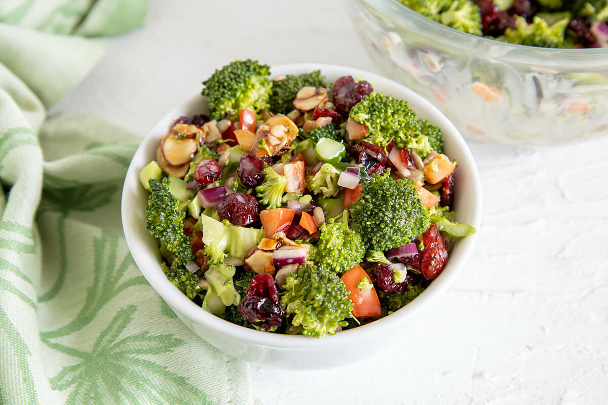 Vegan Broccoli Salad in a bowl with large bowl in the background.