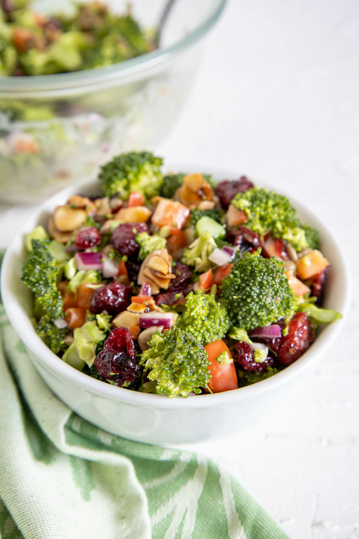 Vegan Broccoli Salad in a bowl with large bowl in background.