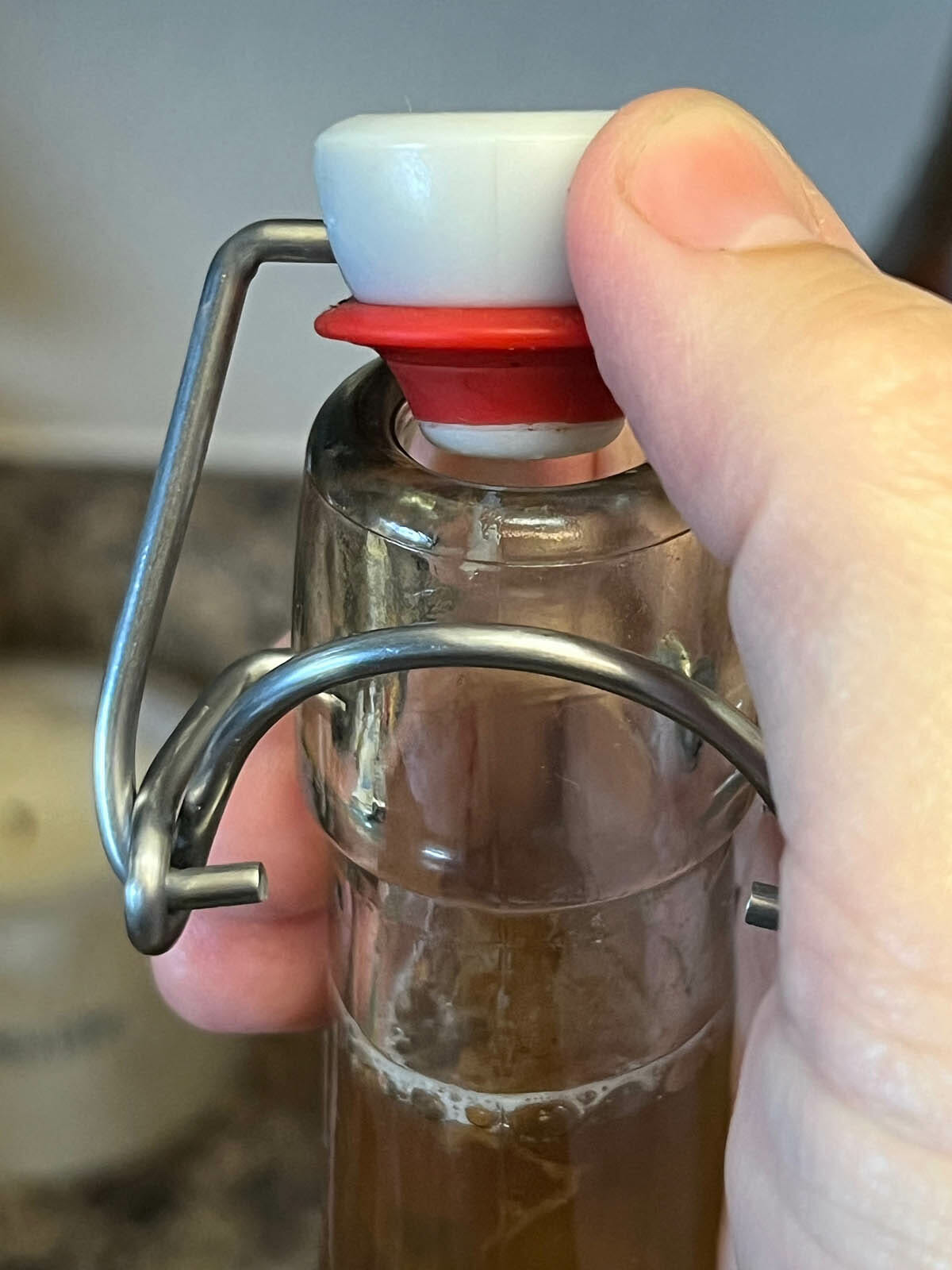 Flip-top bottle with primary fermentation kombucha and pomegranate juice being popped open.