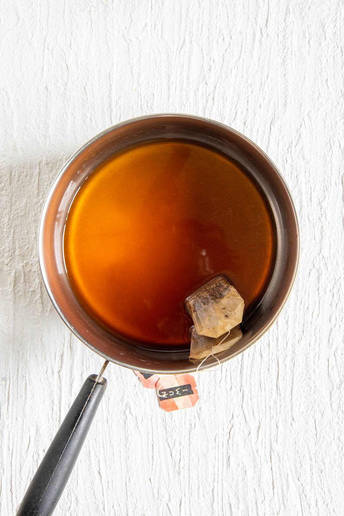 Chai tea bag steeping in a saucepan with water.
