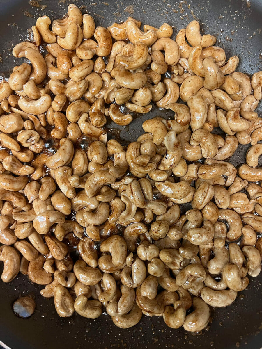 Cashews in skillet after being cooked in maple syrup mixture.