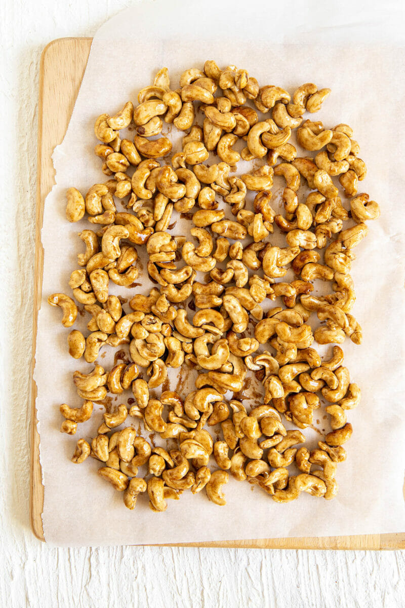 Candied cashews spread on a piece of parchment paper.