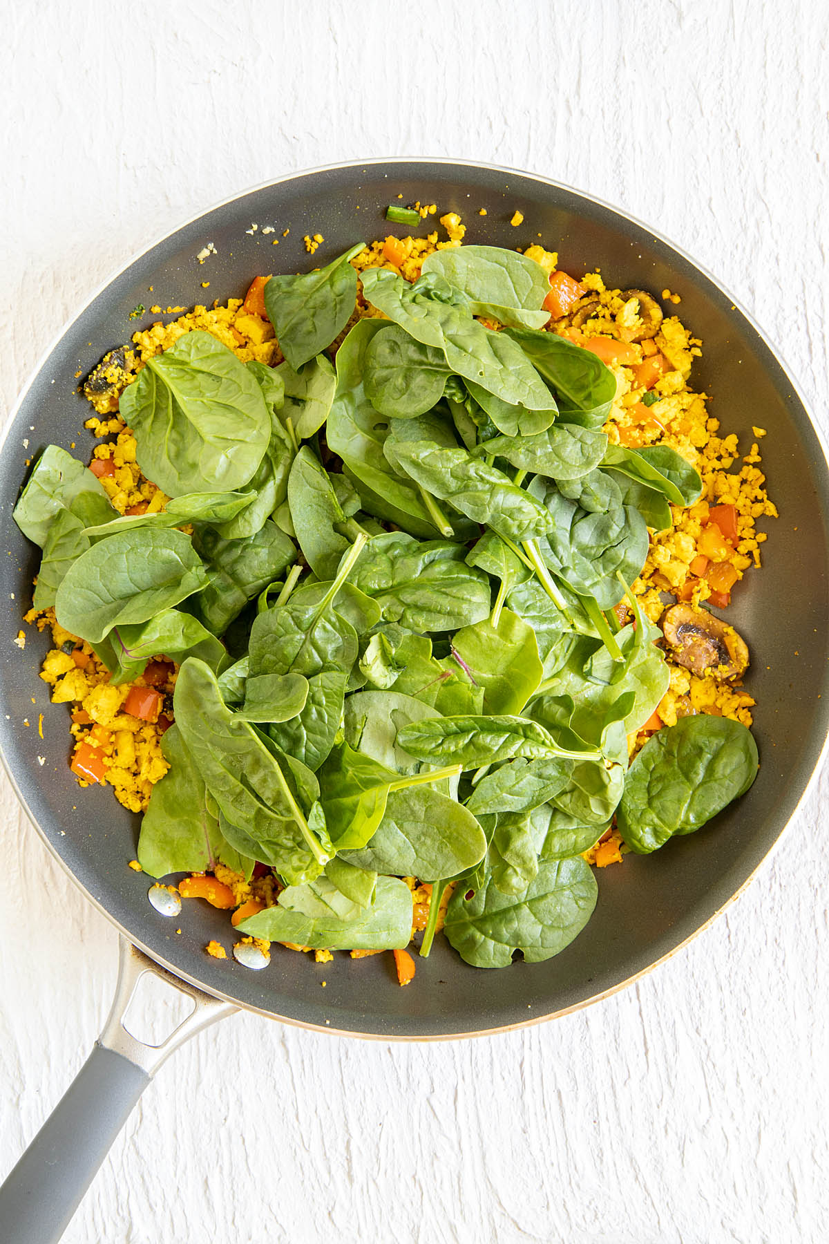 Spinach added to the skillet with tofu and veggies.