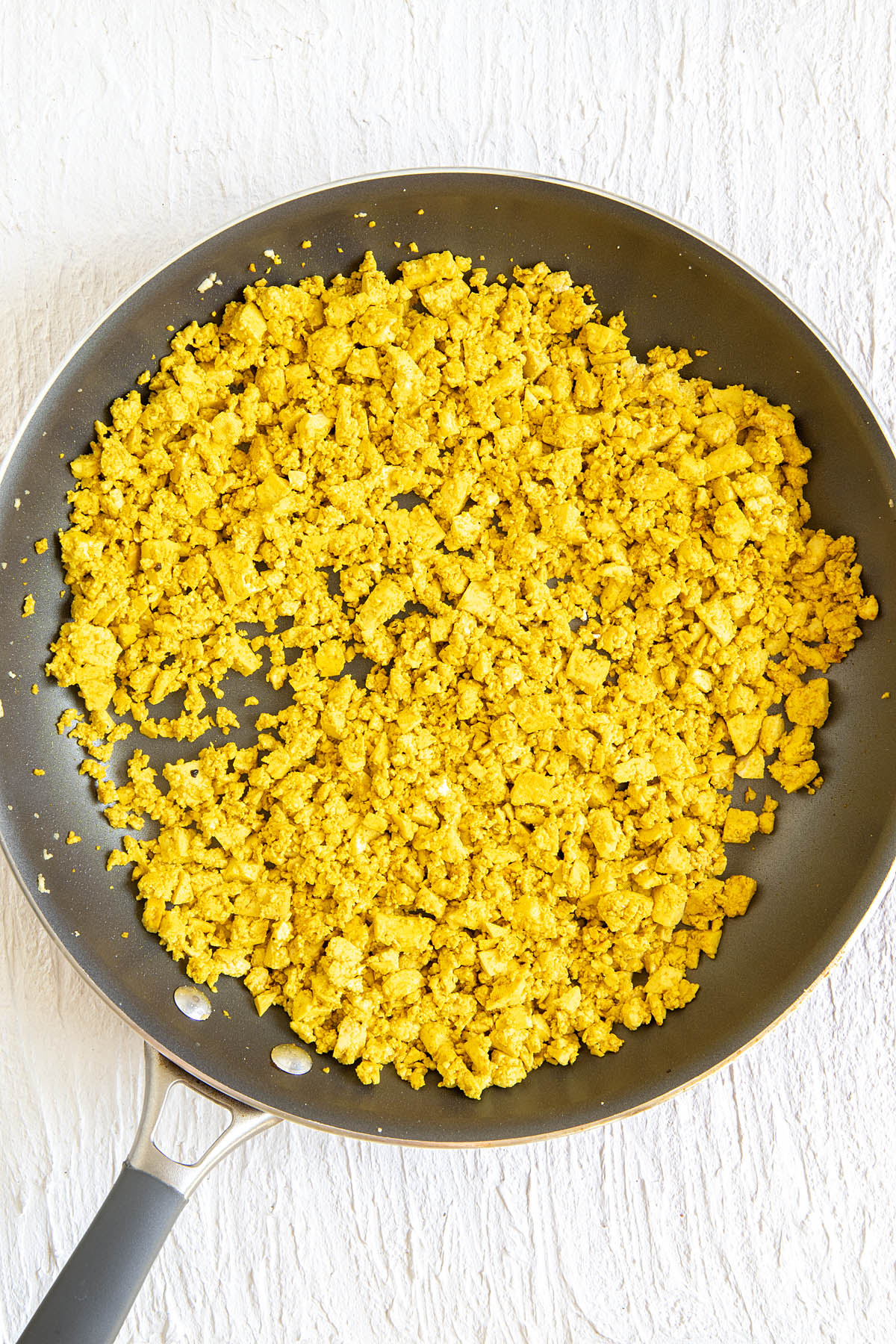 Tofu in a skillet with spices added.