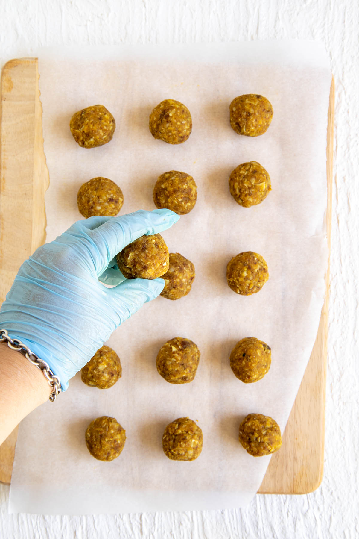 Turmeric balls on parchment paper and one in a gloved hand.