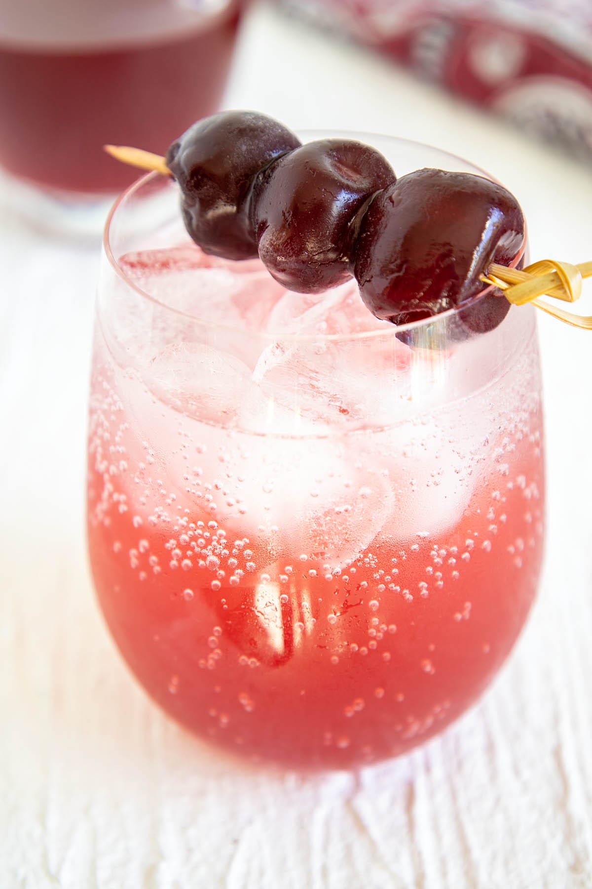 Cherry Shrub in a glass with club soda with cherries on top.