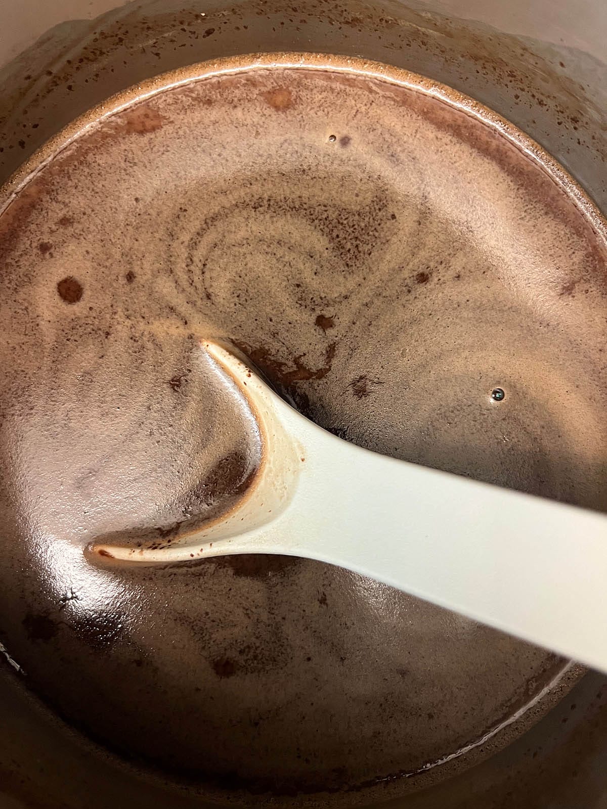Mint hot chocolate in a saucepan with spoon.
