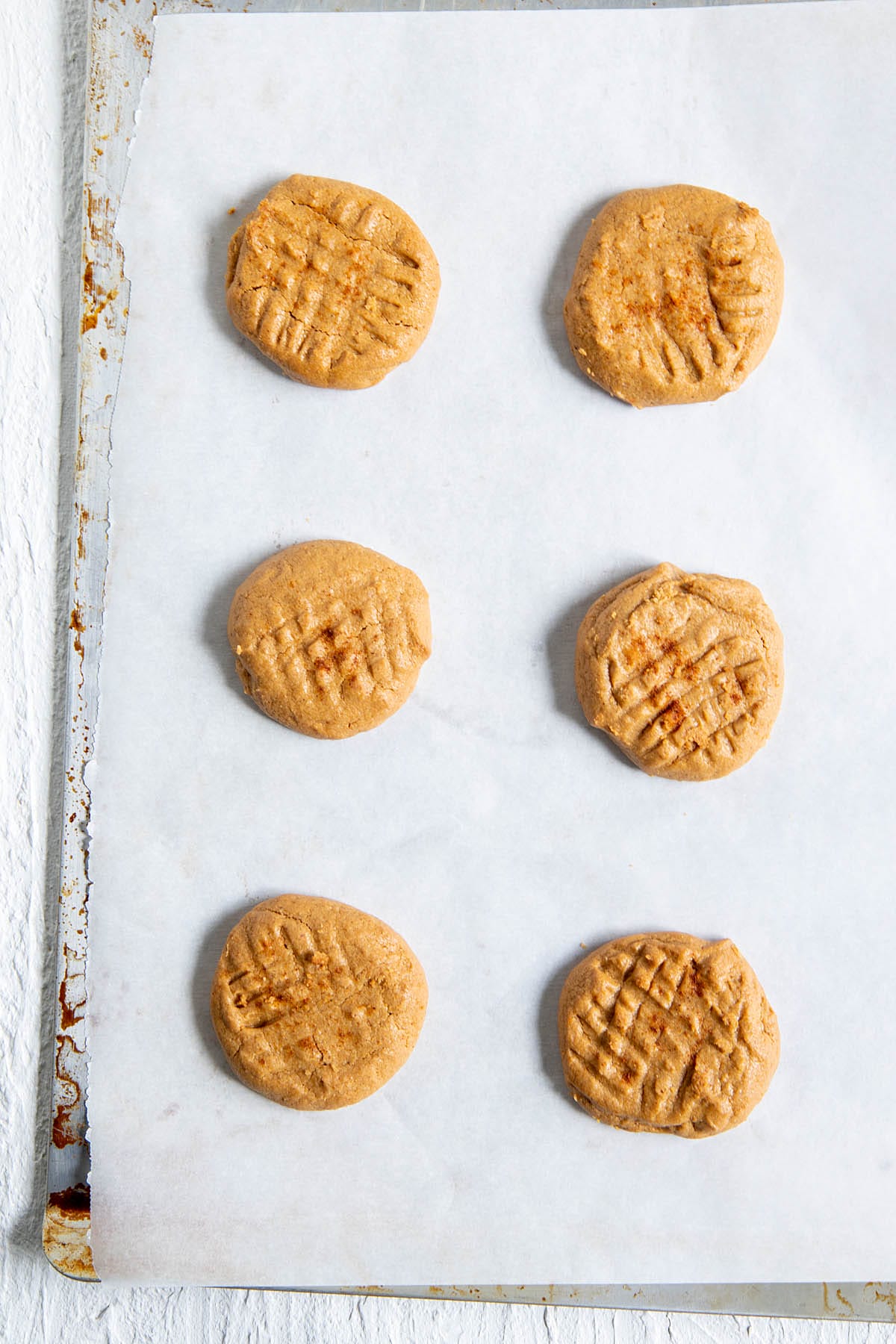 Baked egg free peanut butter cookies on a parchment-lined sheet pan. 