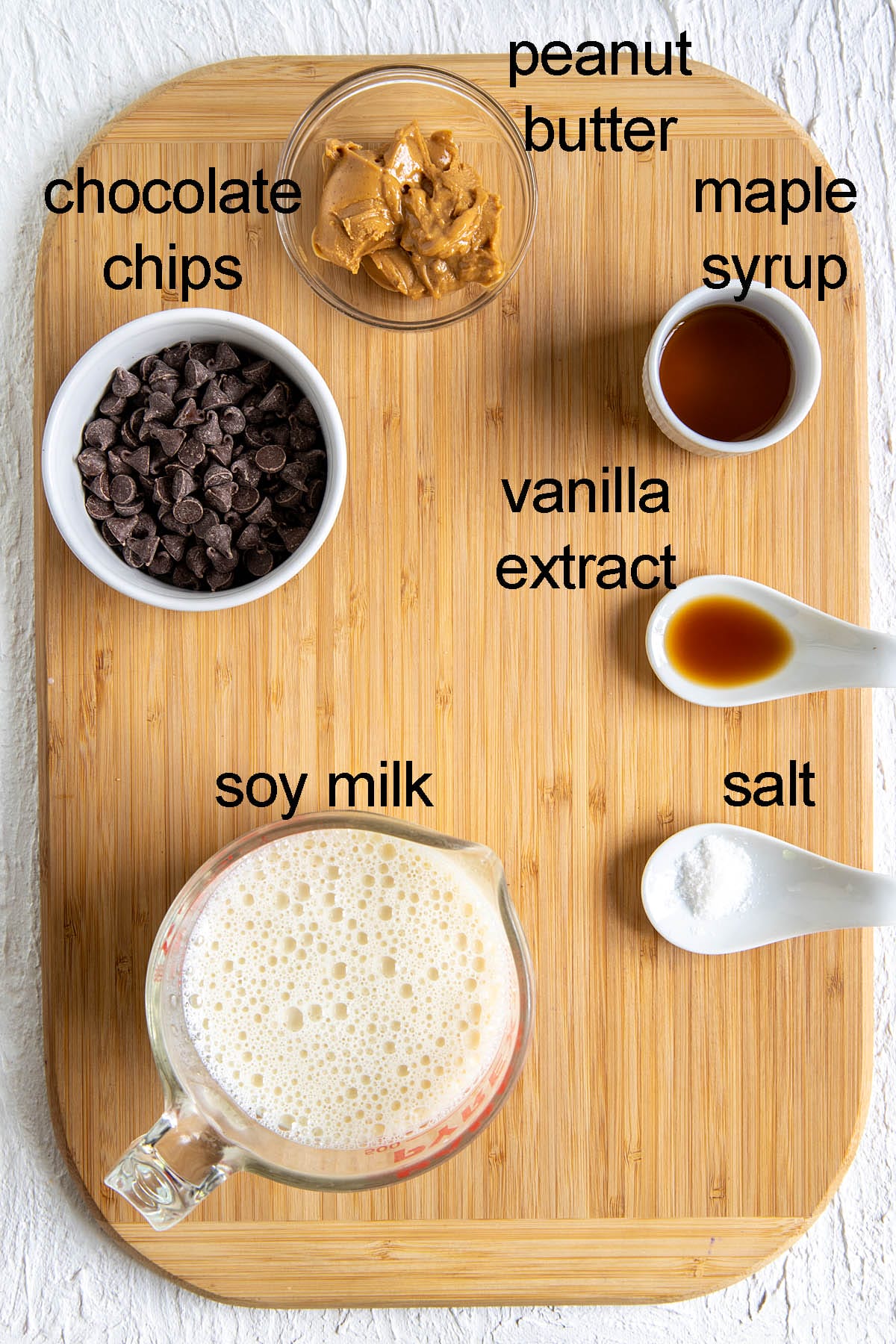 Ingredients for peanut butter hot chocolate on a cutting board with labels.