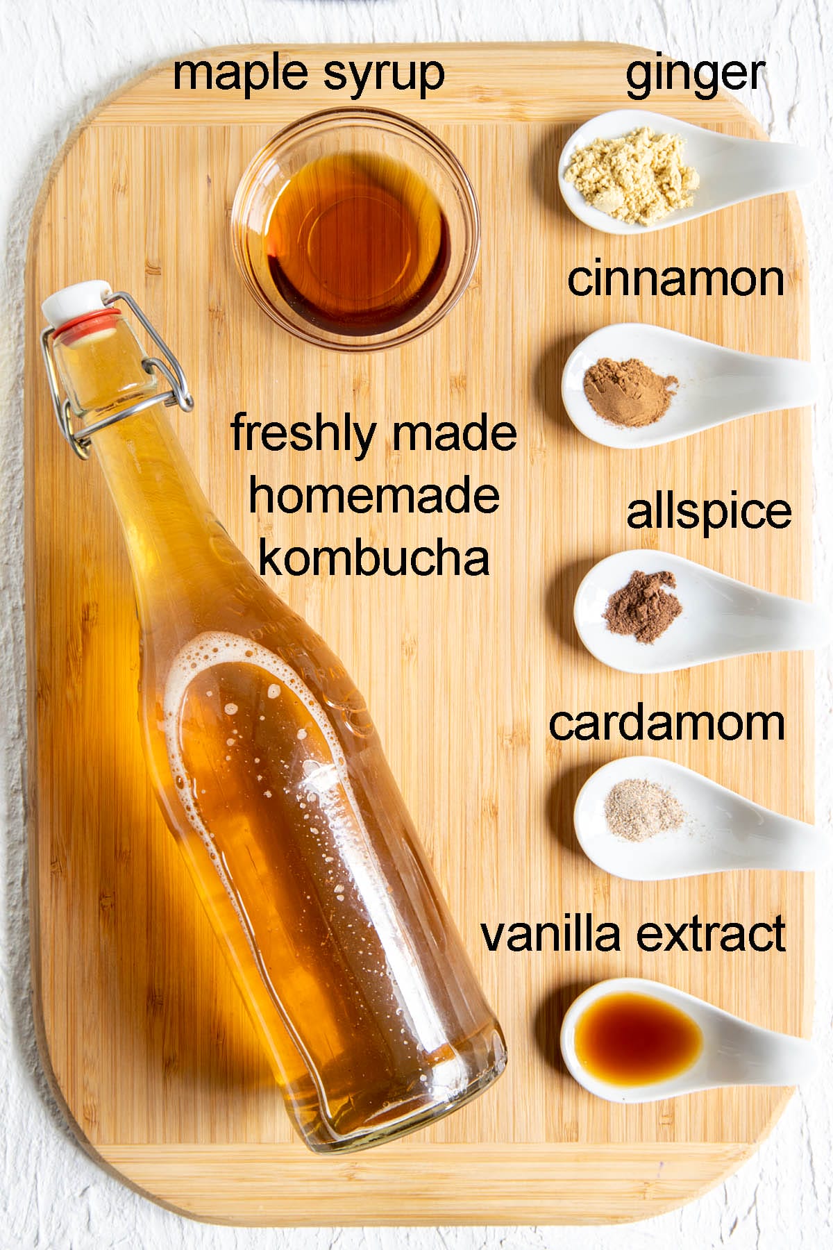 Ingredients for spiced kombucha on a cutting board with labels.