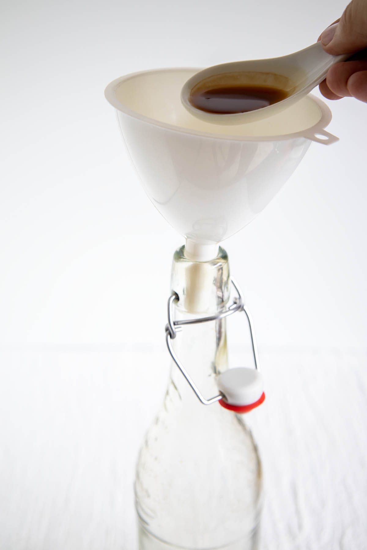 Vanilla extract being poured into a funnel into a bottle.