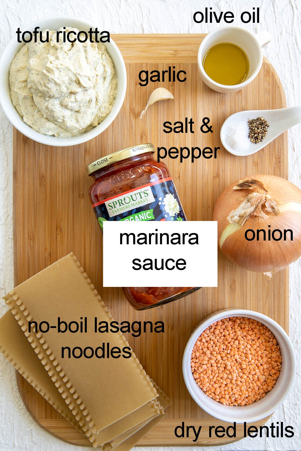 Ingredients for vegan lentil lasagna on a cutting board with labels.