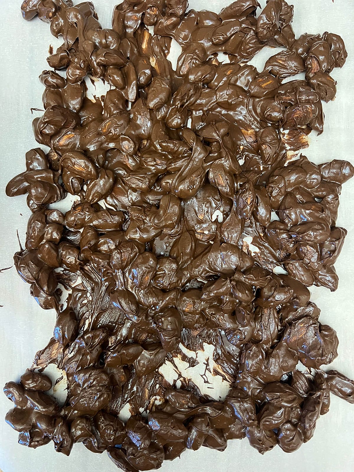 Chocolate covered almonds on parchment paper.