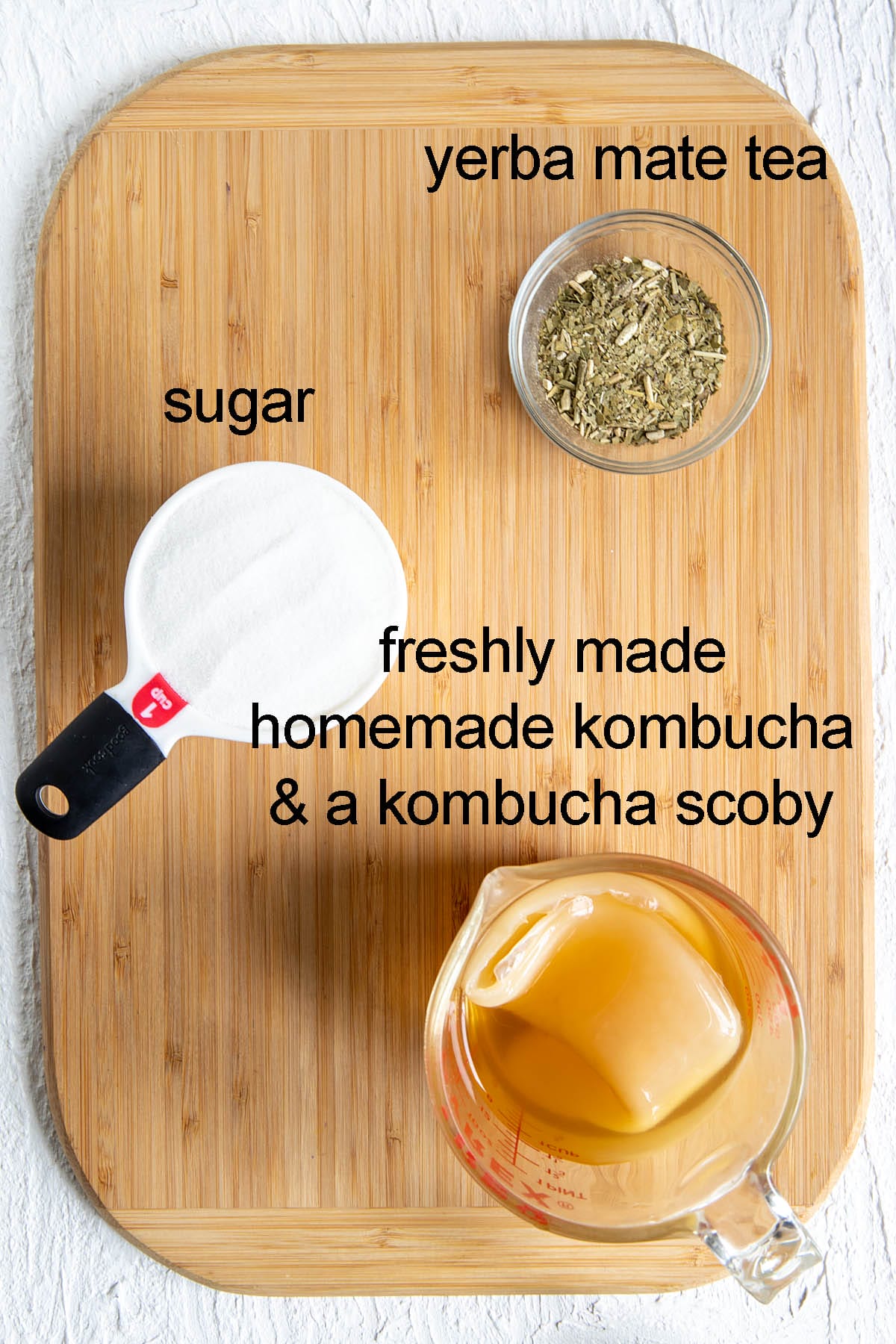 Ingredients for yerba mate kombucha on a cutting board with labels.