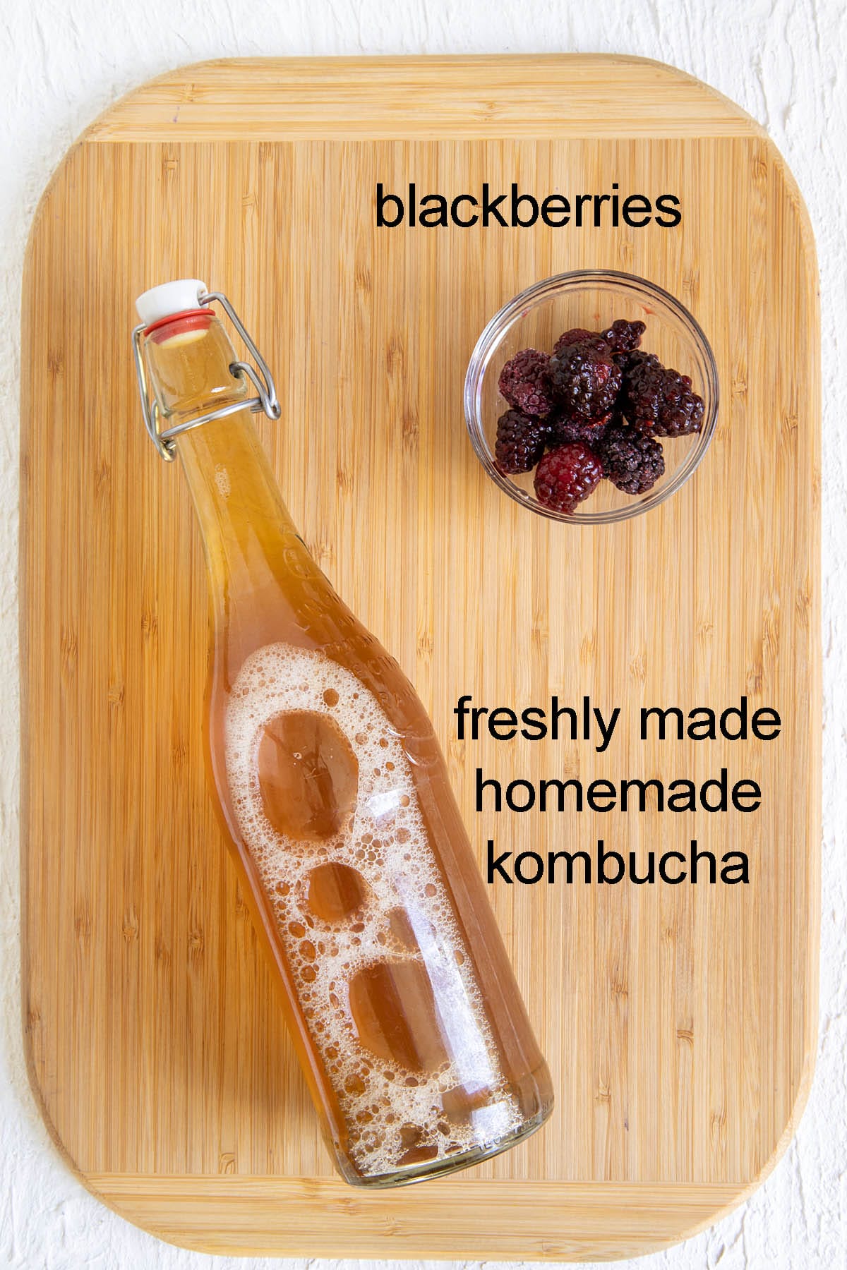 Ingredients for blackberry kombucha on a cutting board with labels.