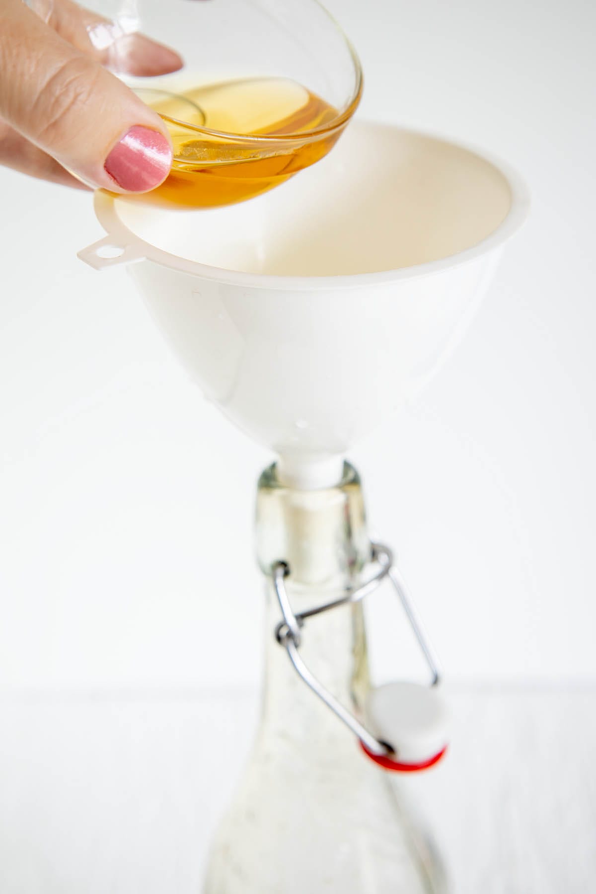Agave syrup being poured into a funnel into a bottle.