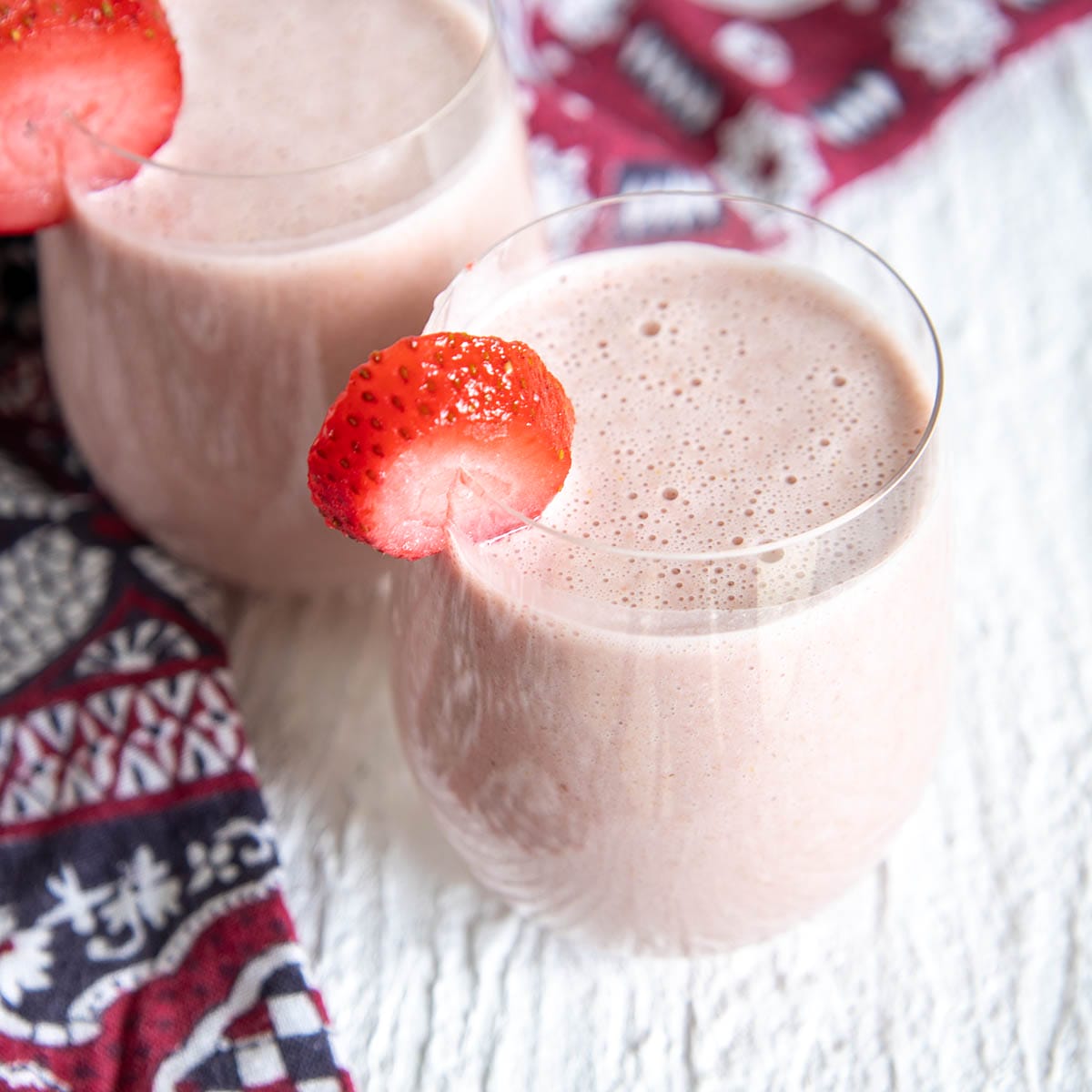 Strawberry Oat Milk in two glasses with sliced strawberries on top.