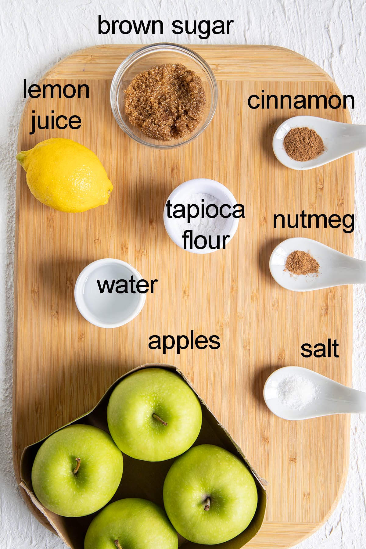 Ingredients for apple crisp filling on a cutting board with labels.