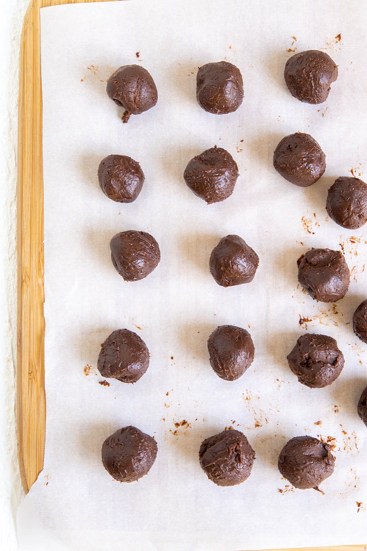 Chocolate truffles on parchment paper on a cutting board.