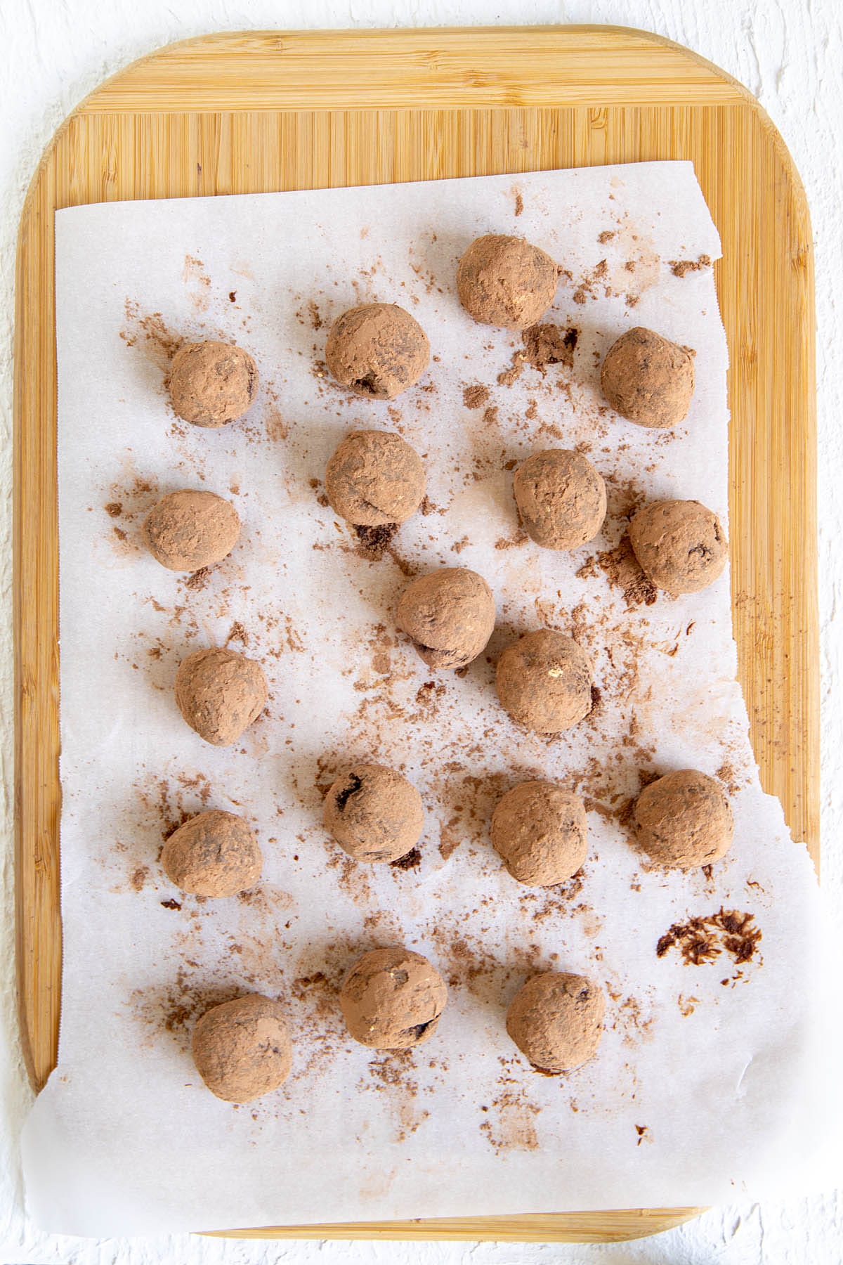 Truffles on parchment paper after rolling in cacao powder and ground ginger.