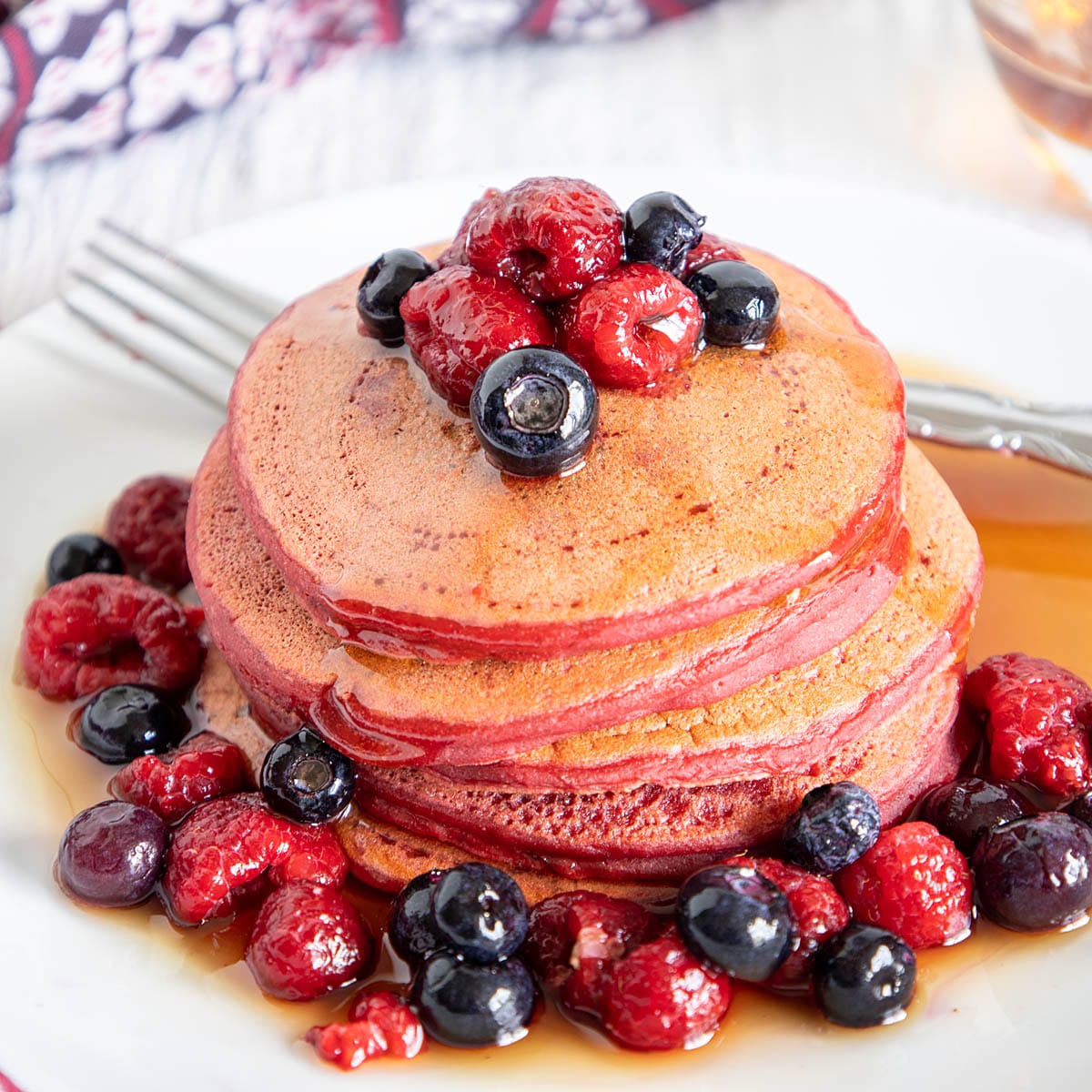 Beetroot Pancakes on a plate with blueberries and raspberries.