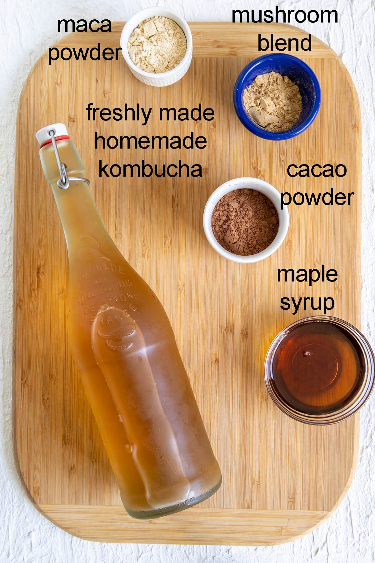Ingredients for chocolate superfood kombucha on a cutting board with labels.