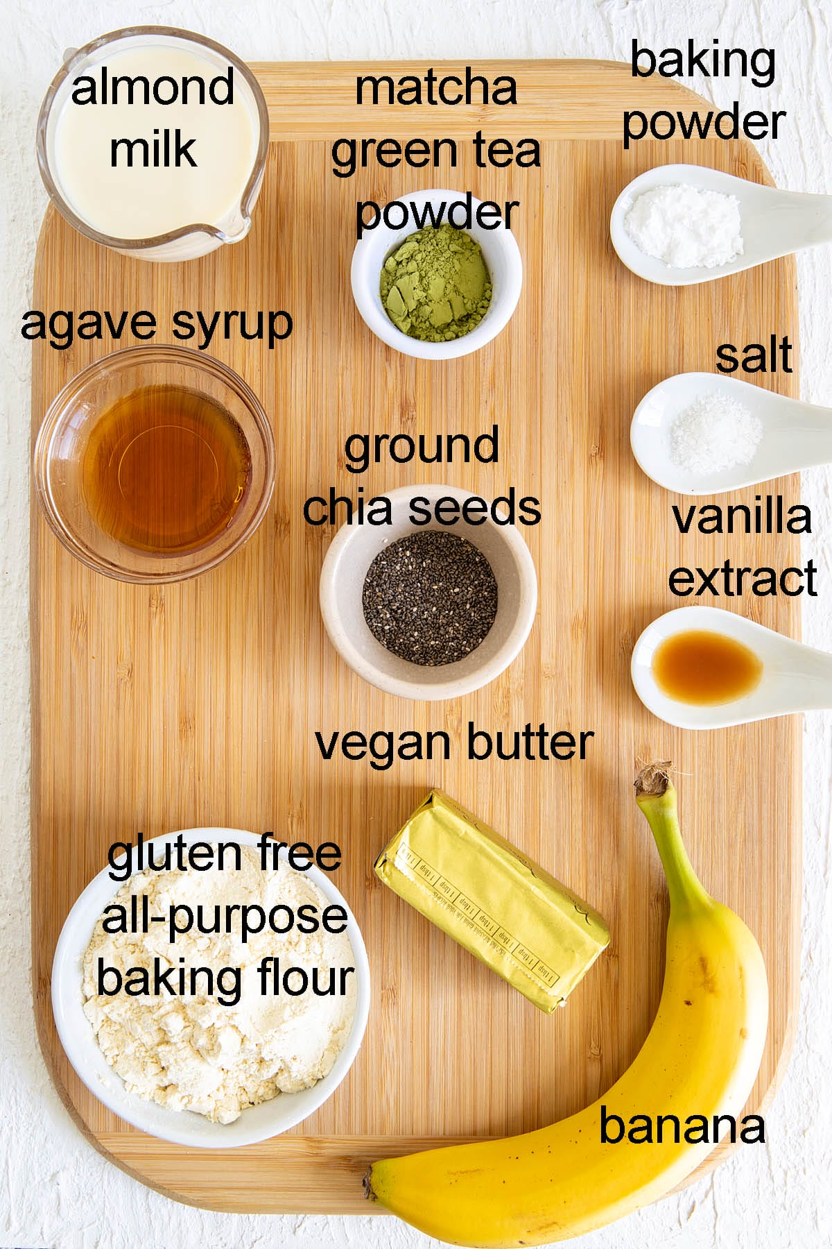 Ingredients for matcha banana pancakes on a cutting board with labels.