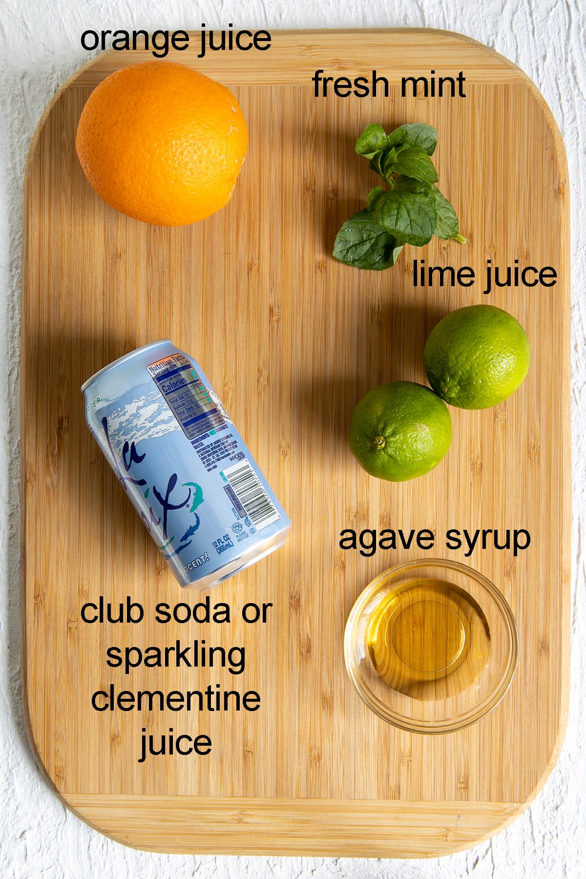 Ingredients for virgin orange mojito recipe on a cutting board with labels.