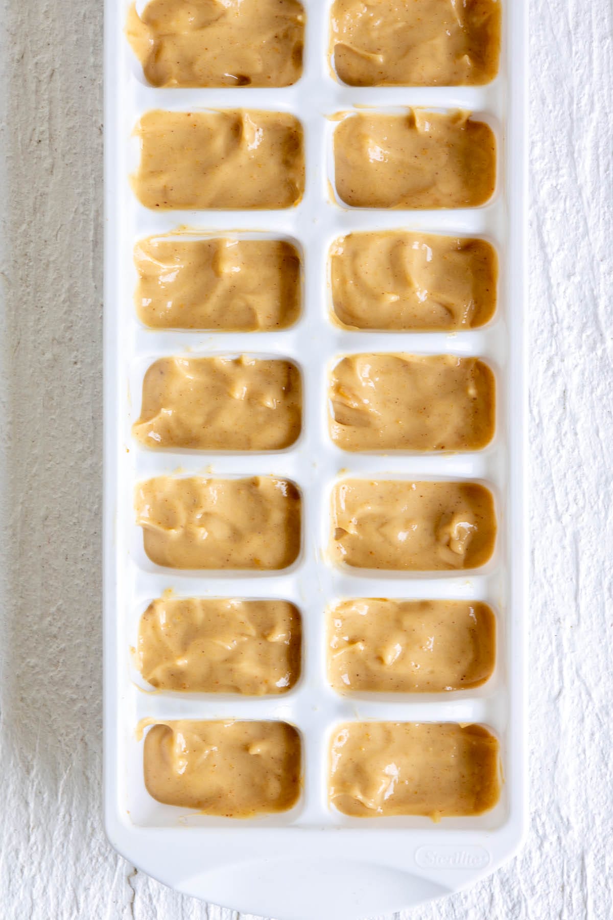 Peanut butter filling in an ice cube tray before freezing.