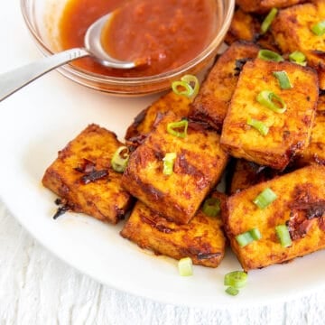 Harissa Tofu On a plate with small bowl of harissa sauce.