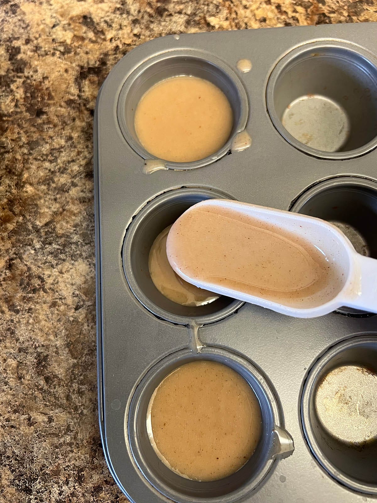 Nog mixture being poured into mini muffin pan.
