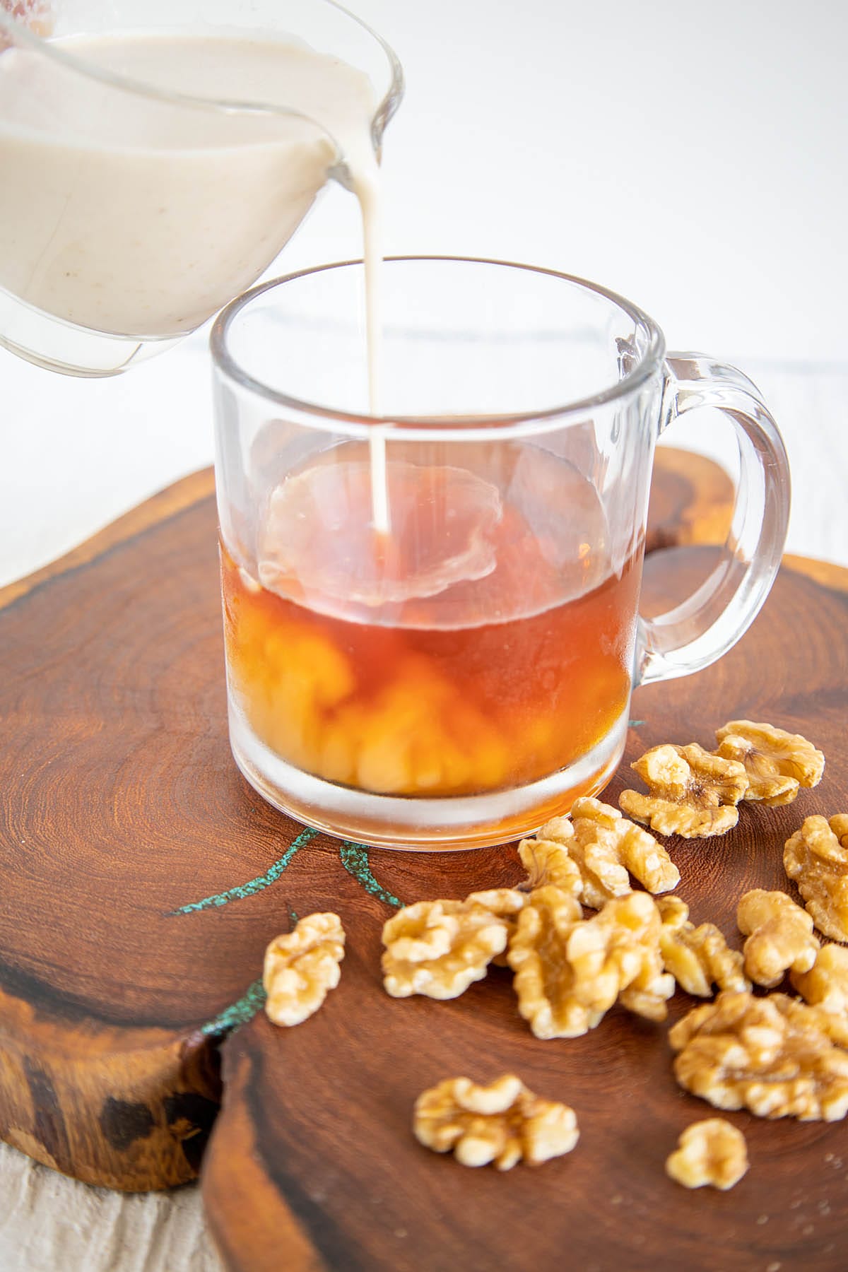Walnut Milk being poured into a mug with tea.