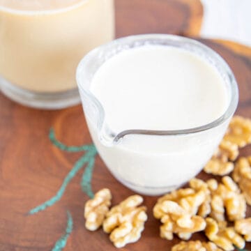 Homemade Walnut Milk in a pitcher with tea in the background.