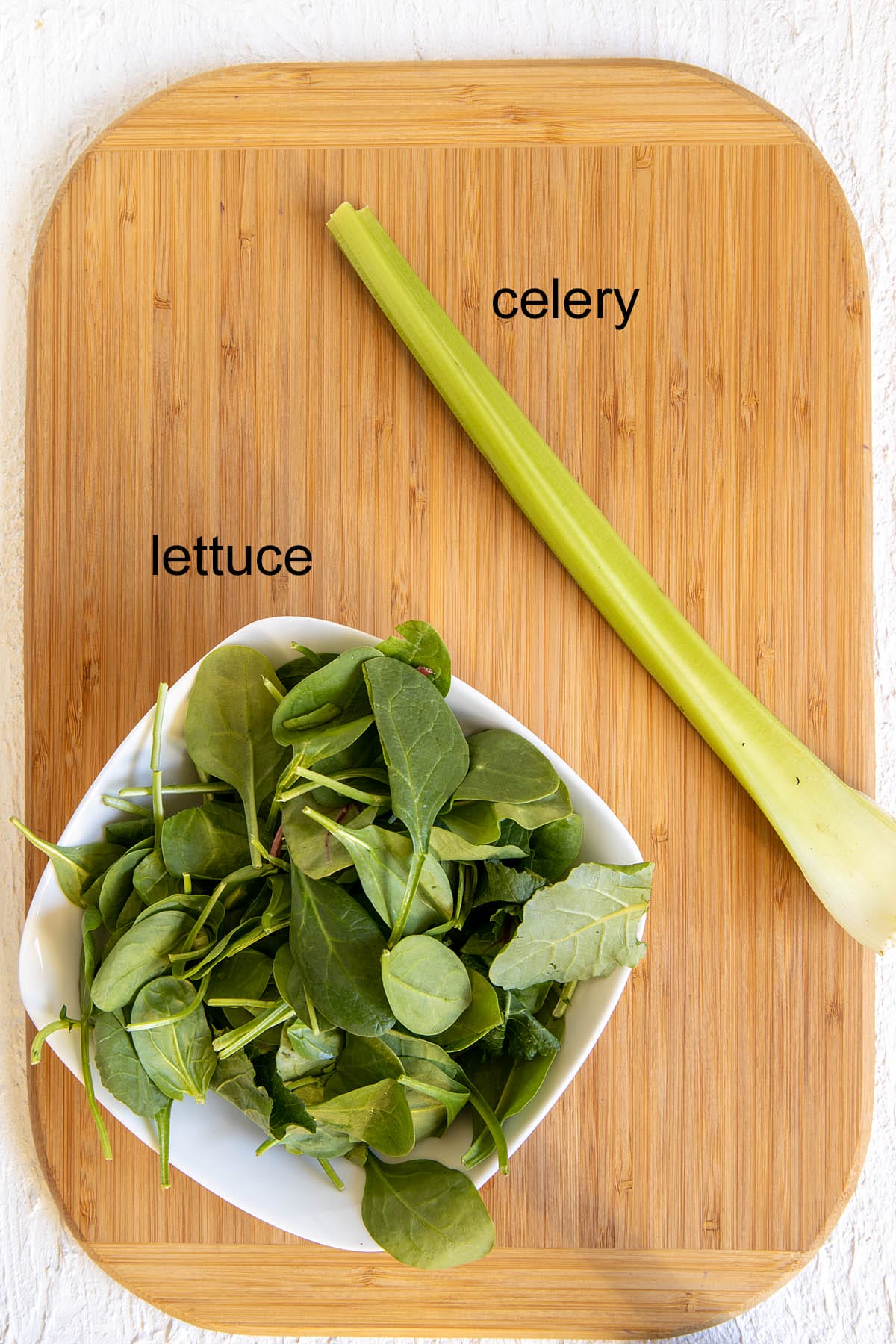 Celery and lettuce on a cutting board with labels.