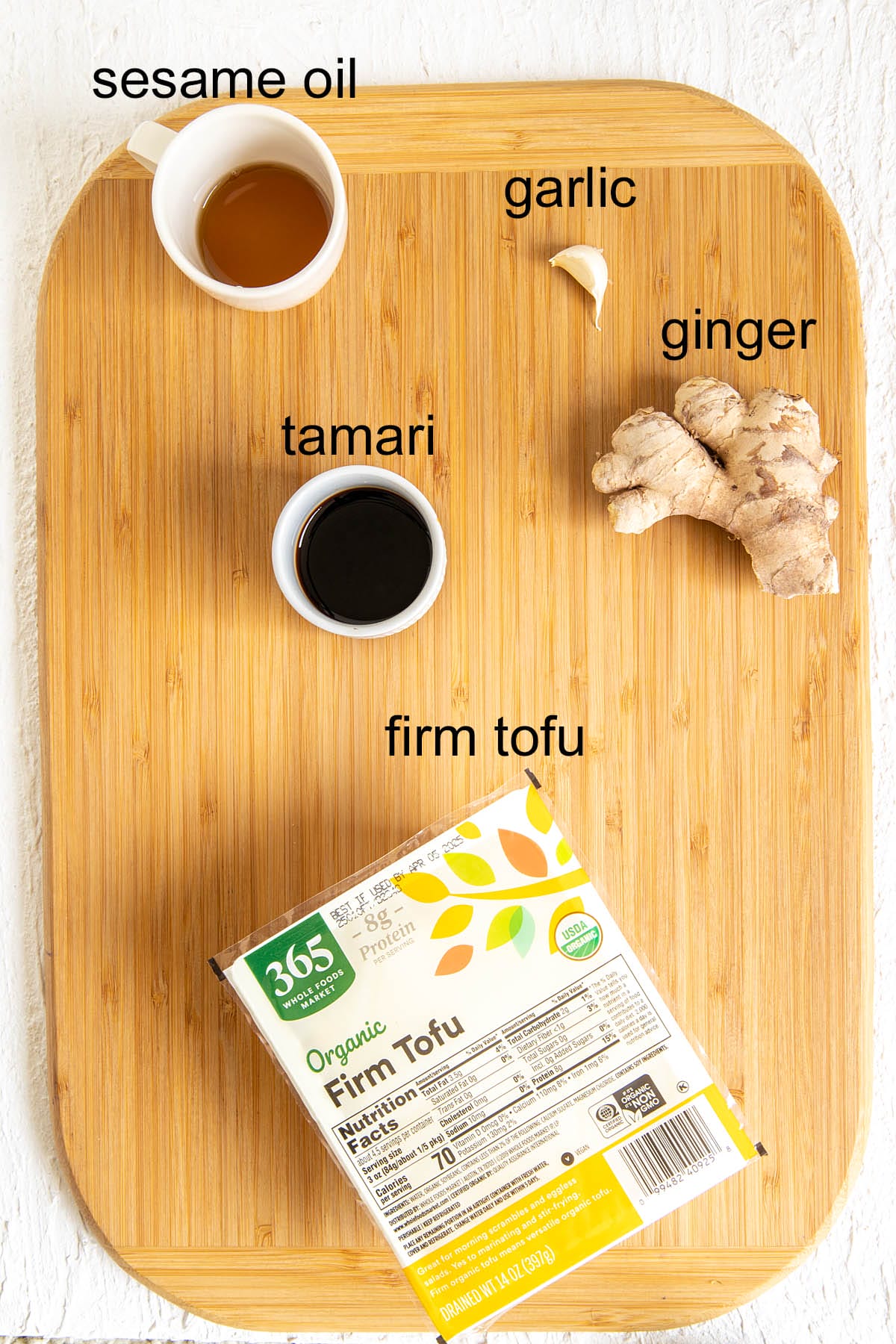 Ginger garlic tofu ingredients on a cutting board with labels.