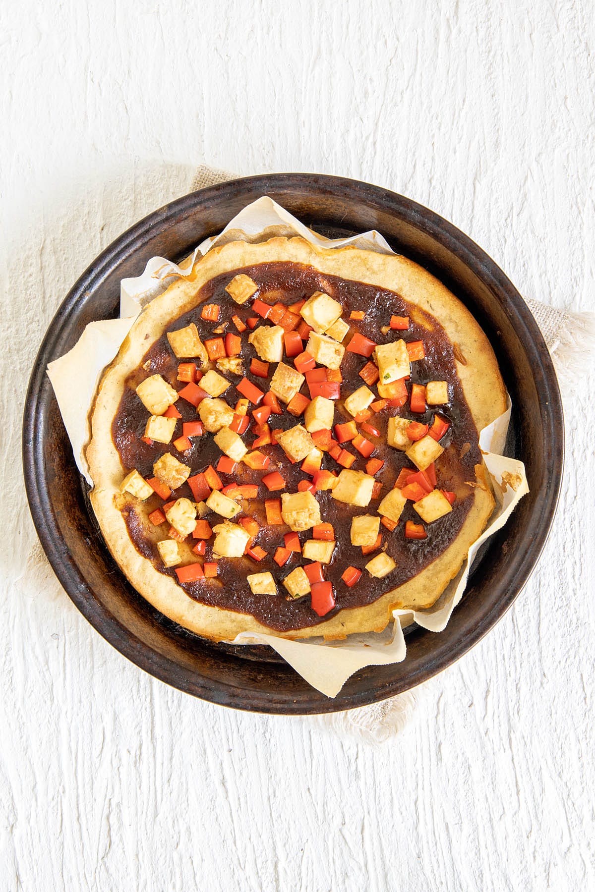 Pizza crust with red pepper, tofu, and hoisin sauce after baking.