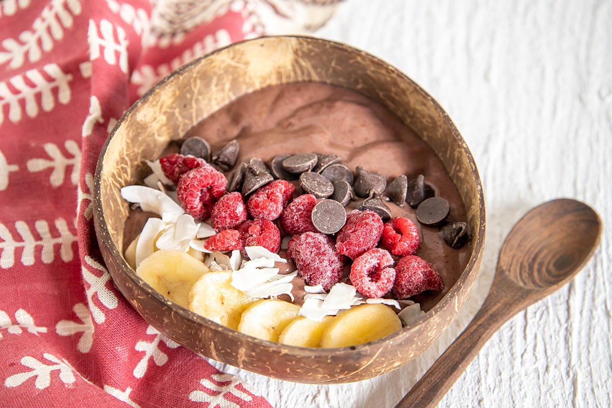 Chocolate Acai Bowl in a wood bowl with spoon.