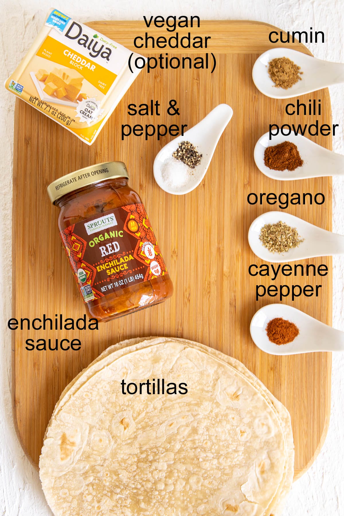 Vegan enchilada ingredients on a cutting board with labels.