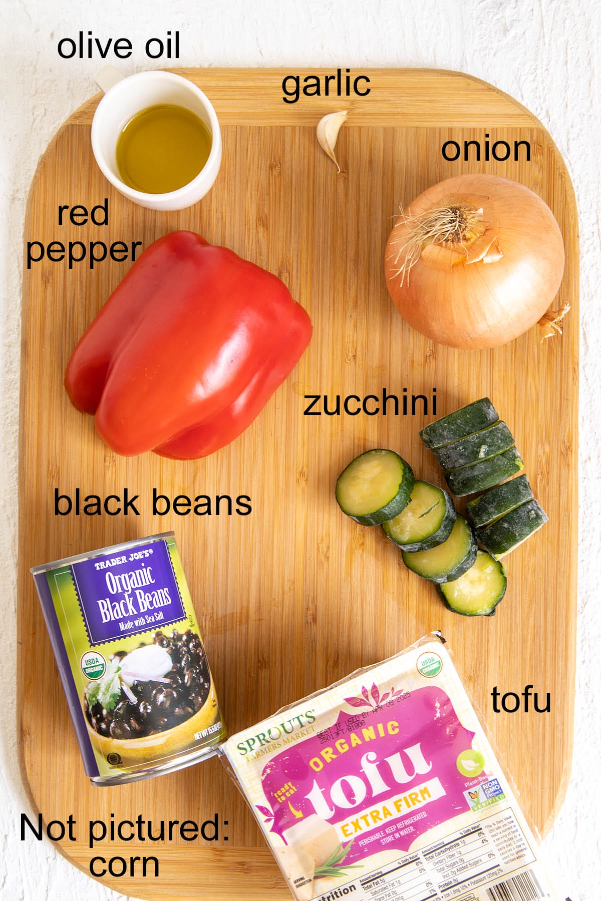 Vegan enchilada ingredients on a cutting board with labels.