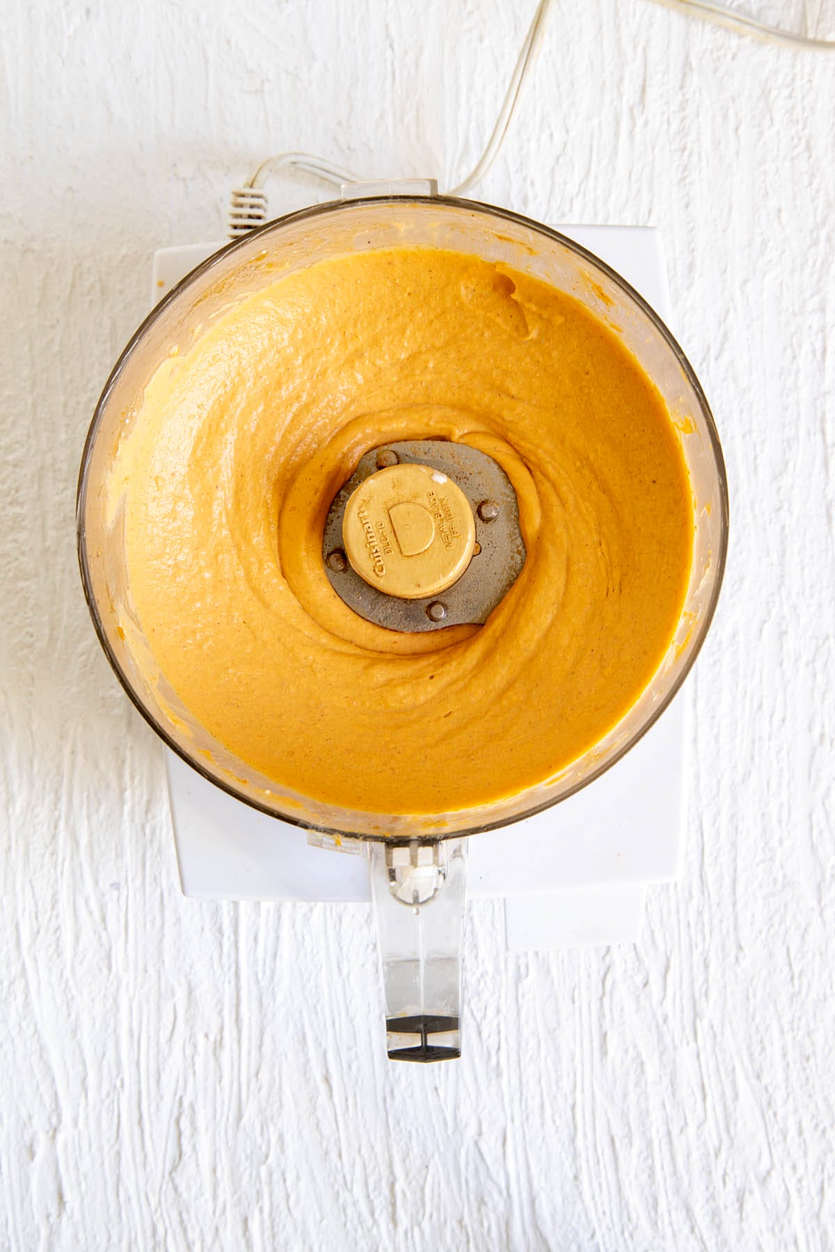 Cheesecake filling ingredients in a food processor after blending.