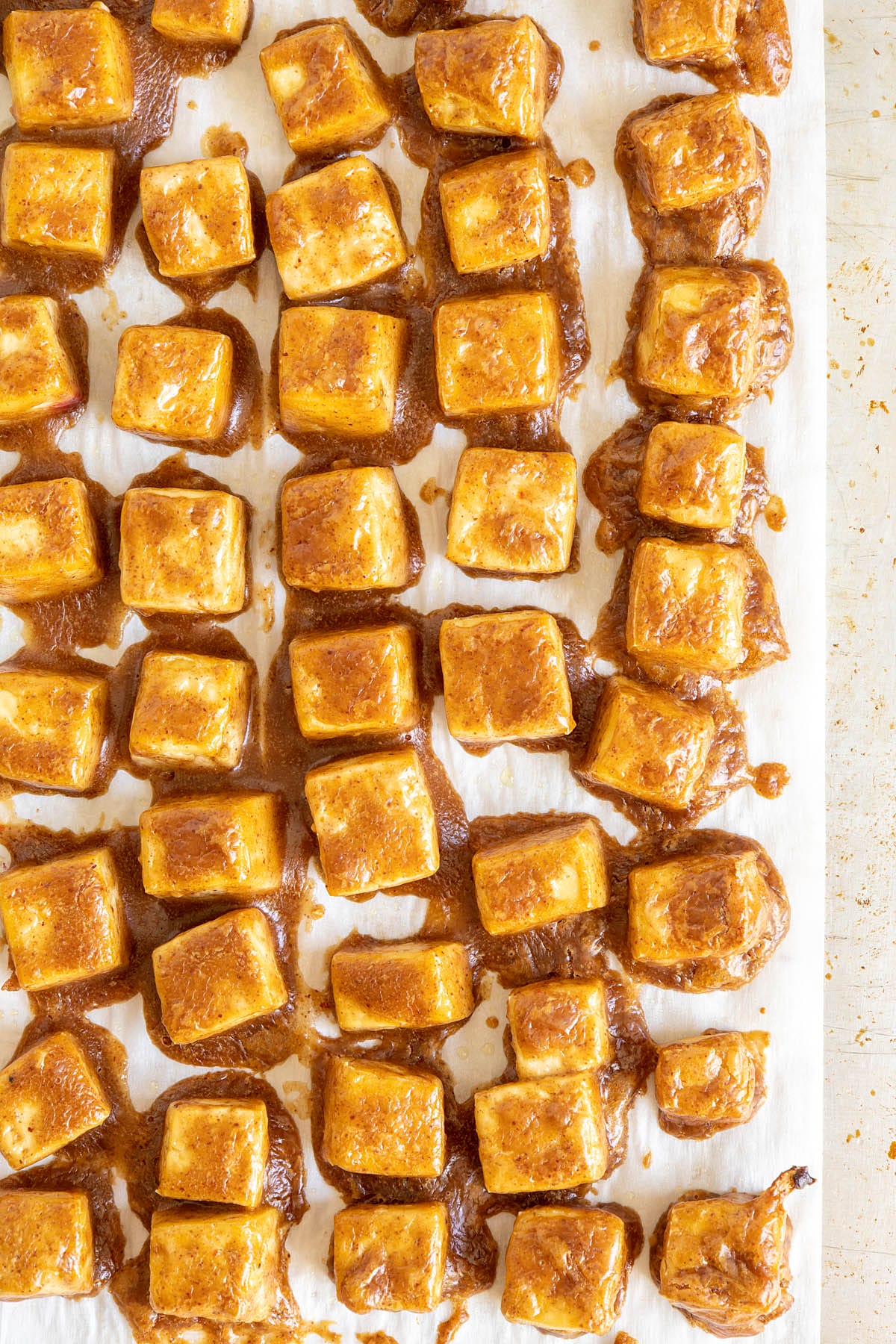 Baked tofu with  peanut sauce on a parchment paper lined baking sheet.