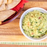 Bowl of guacamole with baked tortilla chips.